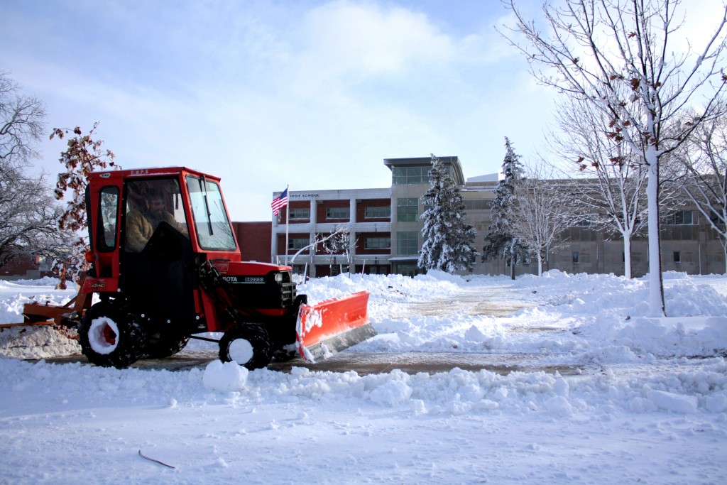 Snow plow clearing sidewalk in front of school
